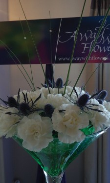 Martini vase with white carnations, eryngium and steel grass arranged in green crystal gel