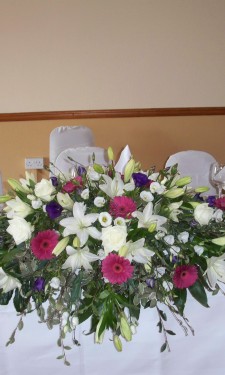Top table arrangement of ivory lily, lizianthus, pink gerbera and purple lizianthus