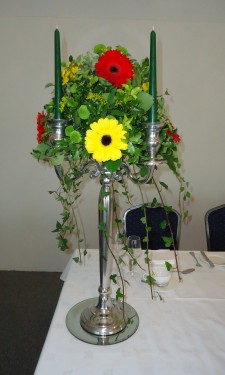 Candelabra arrangement with red and yellow gerbera and green spray chrysanthemum