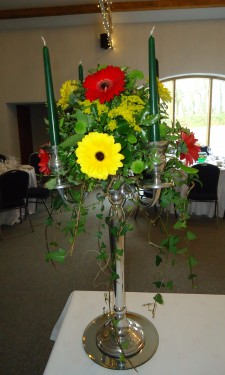 Candelabra arrangement with red and yellow gerbera and green spray chrysanthemum