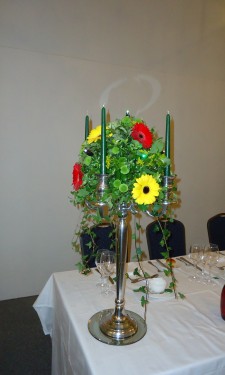 Candelabra arrangement with red and yellow gerbera and green spray chrysanthemum