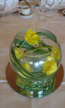 Double yellow tulips in a goldfish bowl with bear grass, clear nuggets, light & mirror tile