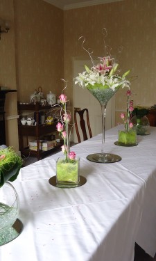 Variety of table centres with arrangements in a martini vase, tank vase and goldfish bowl