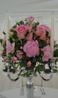 Round arrangement of peony, roses, spray roses and freesia on candelabra