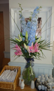 pink lilies and blue delphiniums with steel grass and palm leaves