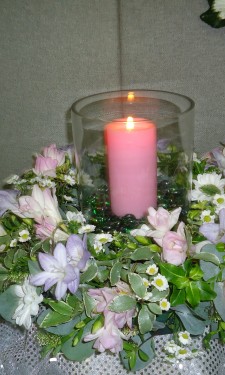 Hurricane vase with candle surrounded by pink and lilac & white wreath ring