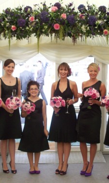 Bridesmaids holding handtied David Austen roses under an arch of roses, hydrangea and liziathus
