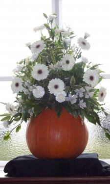 Ivory gerbera, alstromeria, and carnations arranged in a pumkin