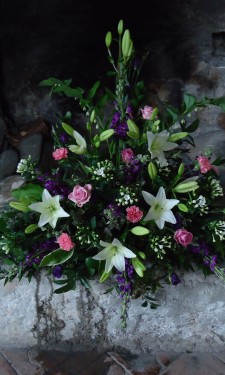 Triangular arrangement of lilies, roses bouvardia, lizianthus and solomon's seal