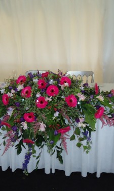 Pink and purple top table arrangement with gerbera, lizianthus, astilbe, freesia and statice
