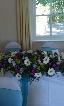 Top table arrangement containing ivory gerbera, yellow alstromeria, pink spray carnations and lilac freesia.
