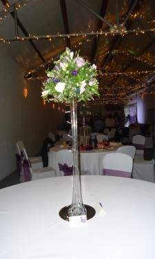 Rose and freesia arrangement on top of lily vase with lights